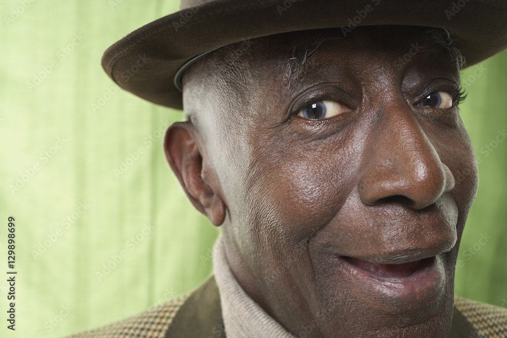 Closeup portrait of an African American senior man wearing a hat against green curtain Closeup portrait of an African American senior man wearing a hat against green curtain