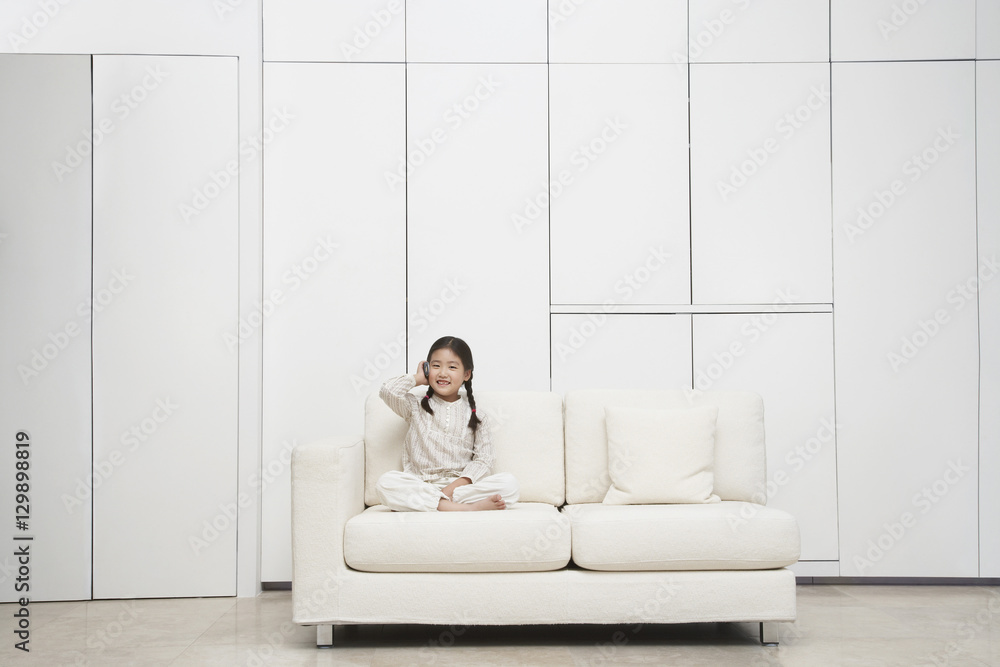Young barefoot girl sitting cross legged on sofa Young barefoot girl sitting cross legged on sofa