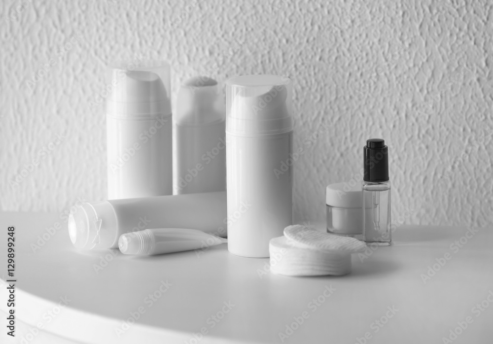 Set of cosmetics on white table against blurred textured background Set of cosmetics on white table against blurred textured background