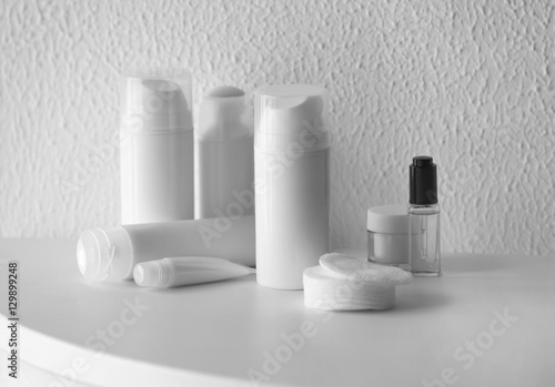 Set of cosmetics on white table against blurred textured background