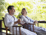 Man and woman in bathrobes sitting in terrace with tea cup