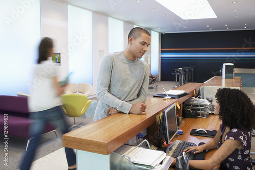 Konstfotografi Man talking to receptionist at the reception desk in office