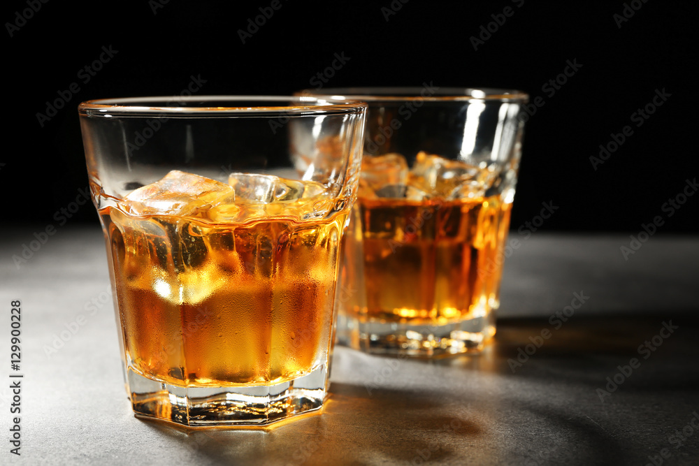 Glasses of whisky on grey textured table closeup