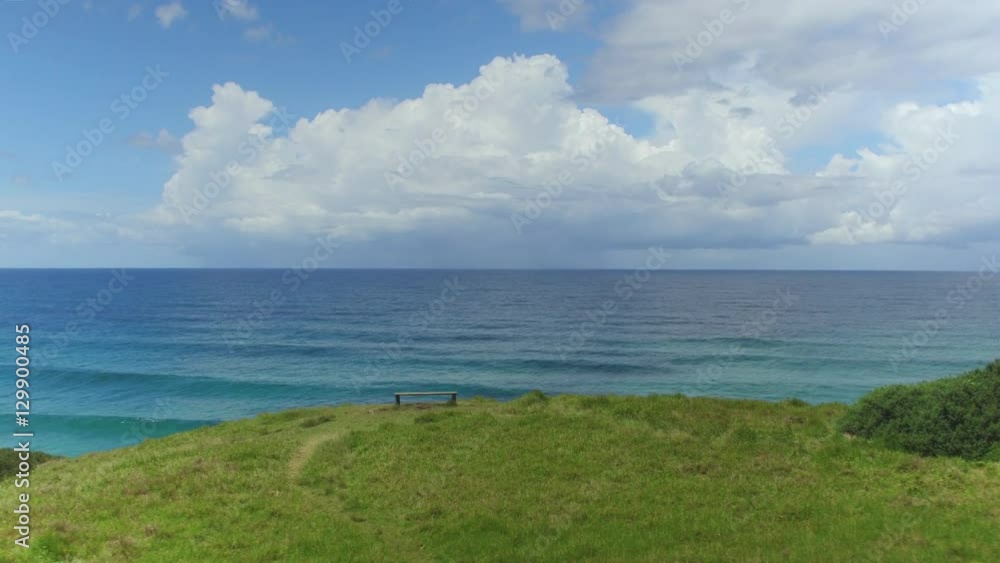 AERIAL: Lonely bench with stunning view of endless turquoise ocean in summer AERIAL: Lonely bench with stunning view of endless turquoise ocean in summer