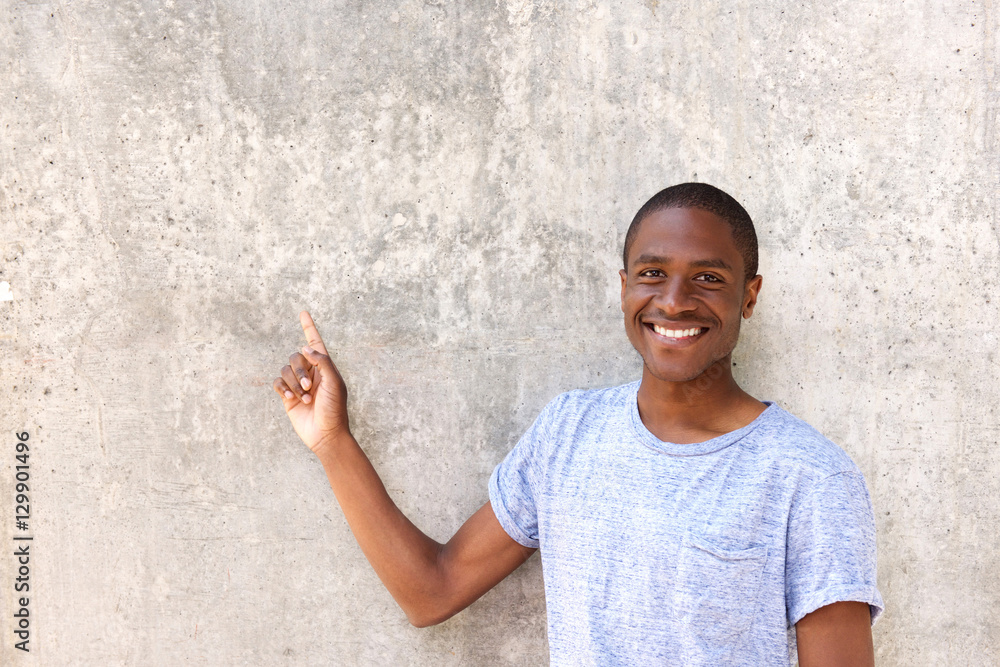 smiling african man in blue t-shirt pointing at copy space smiling african man in blue t-shirt pointing at copy space