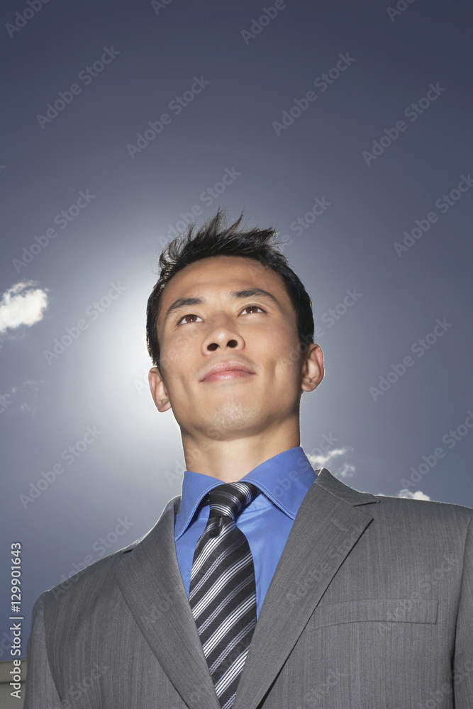 Low angle view of a smiling young businessman against sky