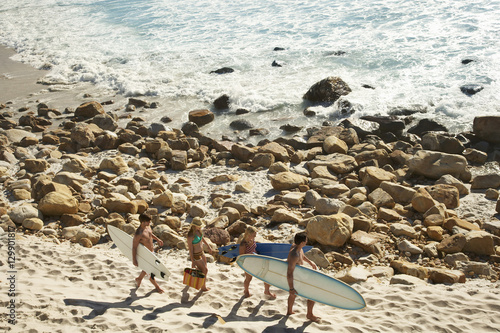 High angle view of young friends carrying surfboards along beach