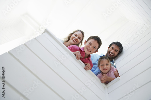 Photography Low angle view of happy parents with children looking over white wall