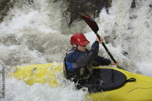 Side view of a man kayaking in rough river