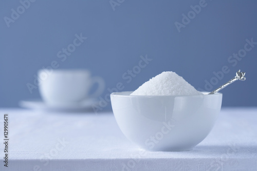 Bowl of sugar on table tea cup in background