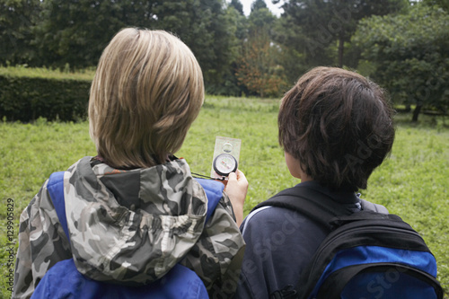 Canvas Print Rear view of two young boys with backpacks using compass