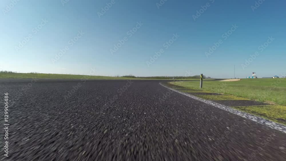 FPV LOW ANGLE: Racecar driving fast competing on racetrack on sunny day