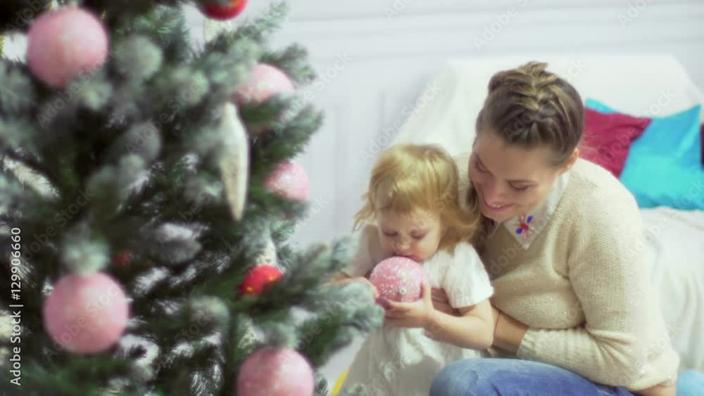 Happy young mother playing with her sweet baby in a decorated room near the christmas tree Happy young mother playing with her sweet baby in a decorated room near the christmas tree