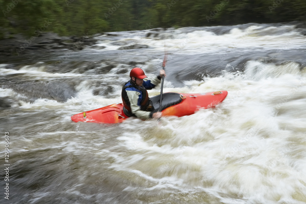 Side view of a man kayaking in rough river