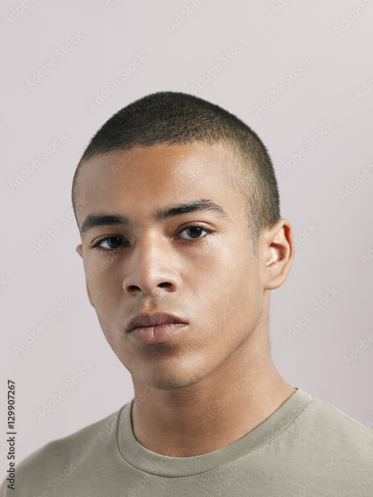 Obraz premium Closeup of young serious man looking at camera on colored background