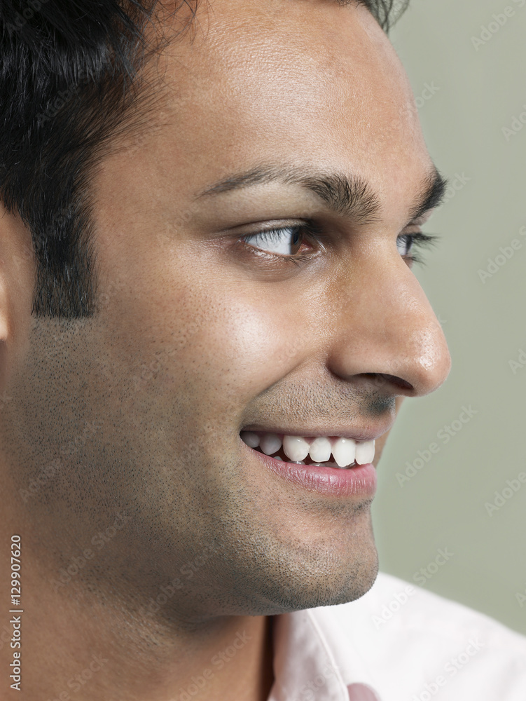 Fototapeta premium Closeup of young Asian man looking away and smiling on colored background