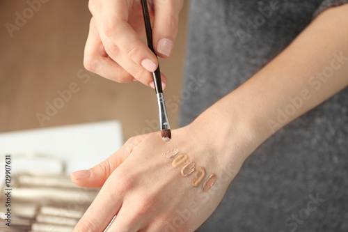 Female visagiste applying cosmetics onto hand