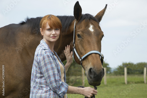 Portrait of a beautiful young woman with horse in field