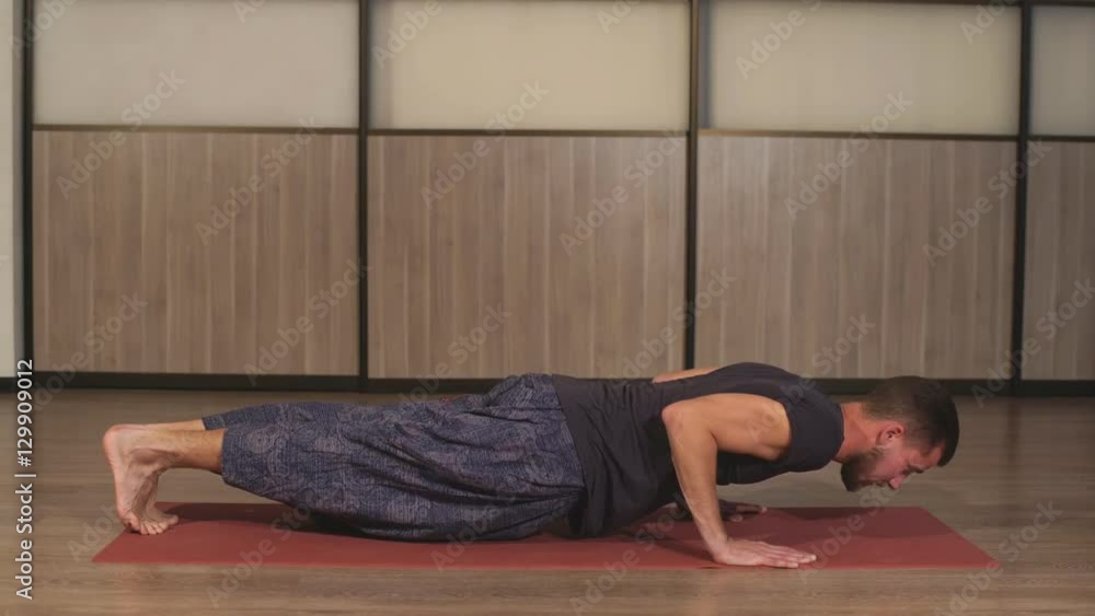 Young yogi men practices yoga asana Chaturanga Dandasana - four-limbed staff pose in studio Young yogi men practices yoga asana Chaturanga Dandasana - four-limbed staff pose in studio