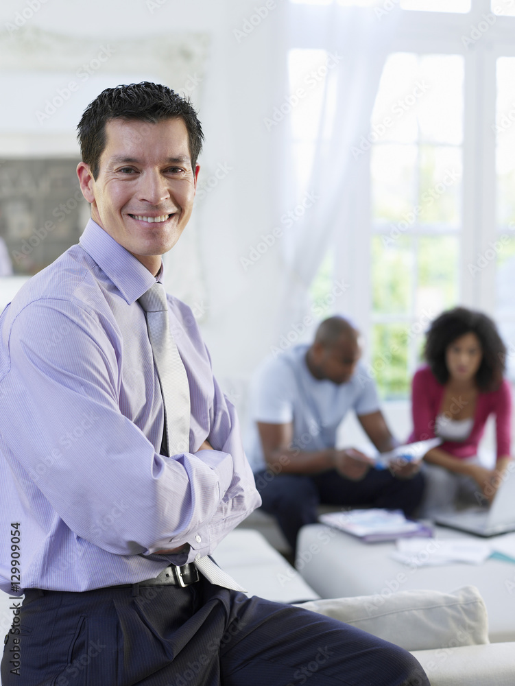 Portrait of a financial consultant with arms crossed and couple sitting in background Portrait of a financial consultant with arms crossed and couple sitting in background
