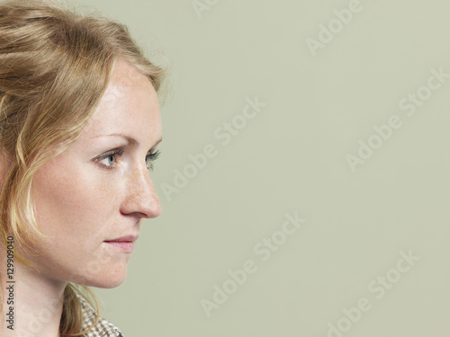 Side view closeup of beautiful young woman looking at copyspace on colored background