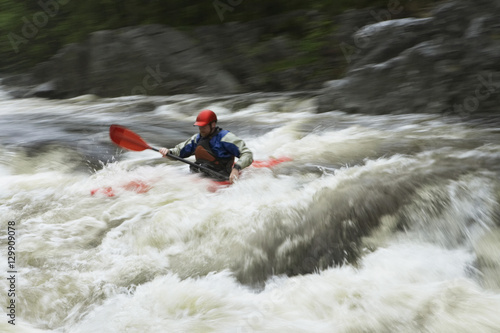 View of a young man kayaking in rough river