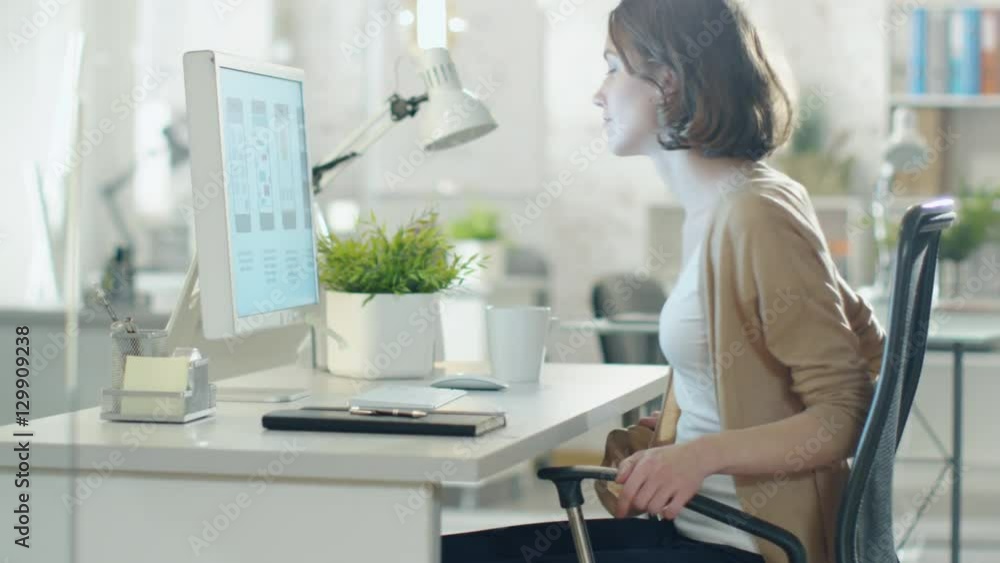 Beautiful Creative Brunette Comes and Sits at Her Desktop Computer. Starts Working on Design. Shot on RED Cinema Camera in 4K (UHD). Beautiful Creative Brunette Comes and Sits at Her Desktop Computer. Starts Working on Design. Shot on RED Cinema Camera in 4K (UHD).