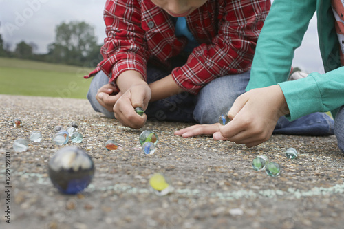 Low section of brother and sister playing marbles on playground
