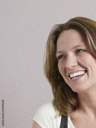 Closeup of beautiful woman looking away and smiling on colored background