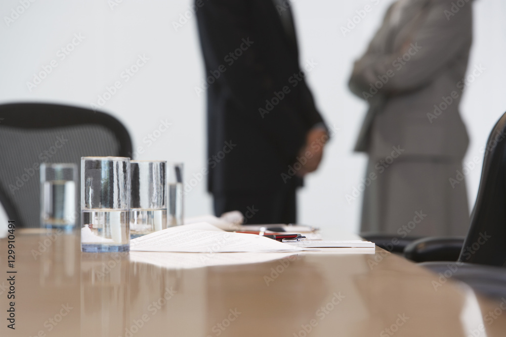 Midsection of a business couple standing with focus on conference table Midsection of a business couple standing with focus on conference table