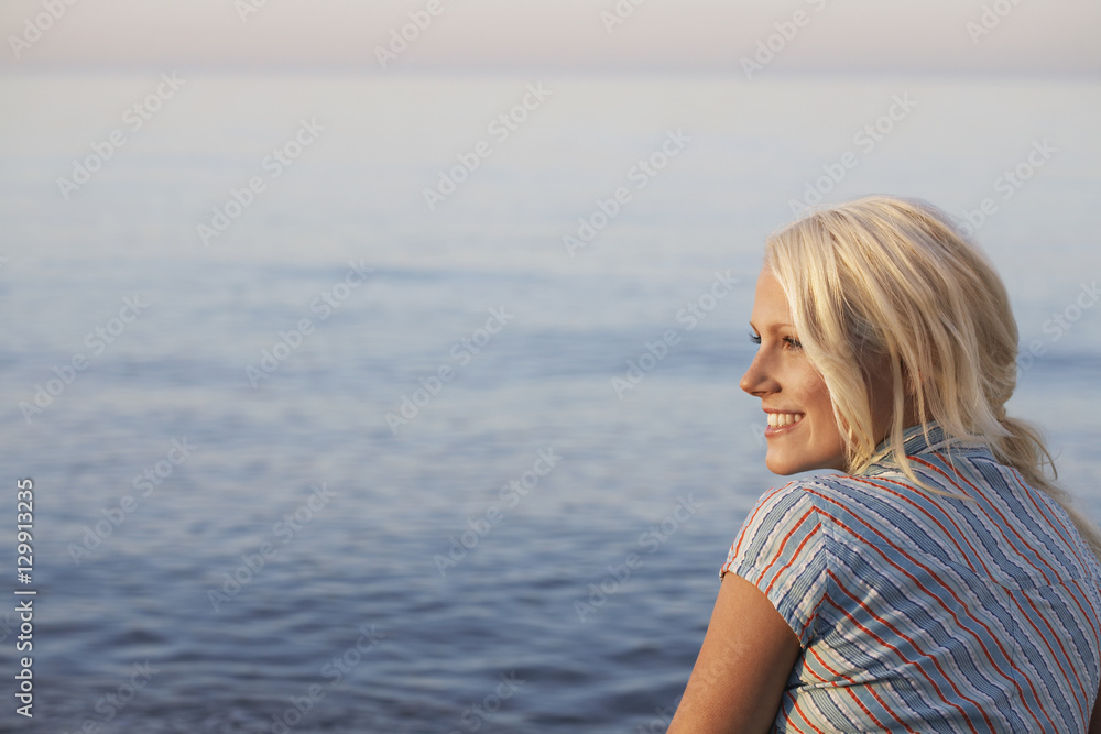 Rear view of beautiful woman looking away while sitting at beach