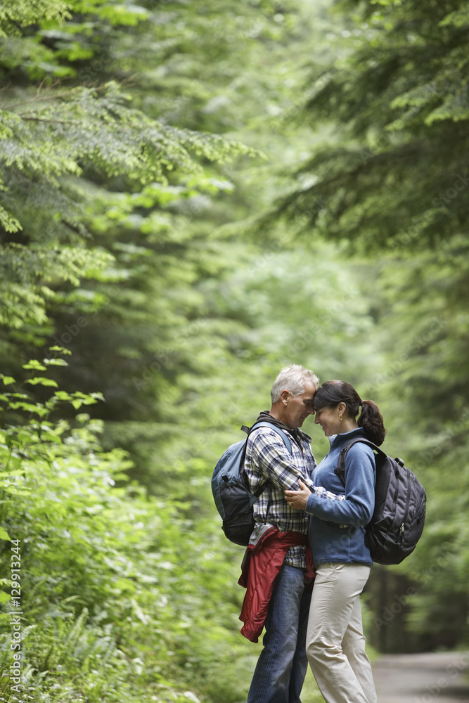 Side view of a middle aged couple embracing on forest road Side view of a middle aged couple embracing on forest road