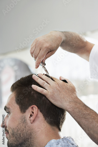 Closeup of man getting an haircut from hairdresser in barber shop