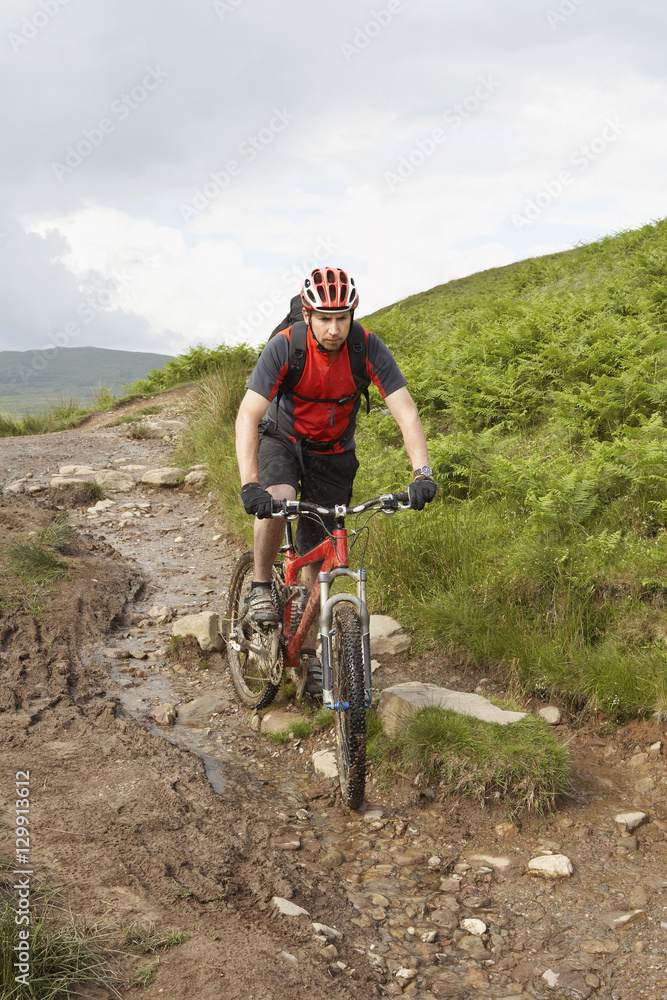 Fototapeta premium View of a male cyclist on countryside muddy track