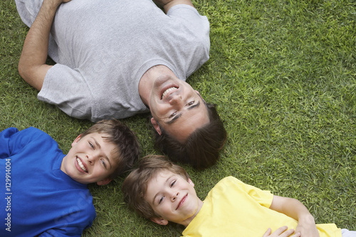 Elevated view of smiling father and two sons lying on grass