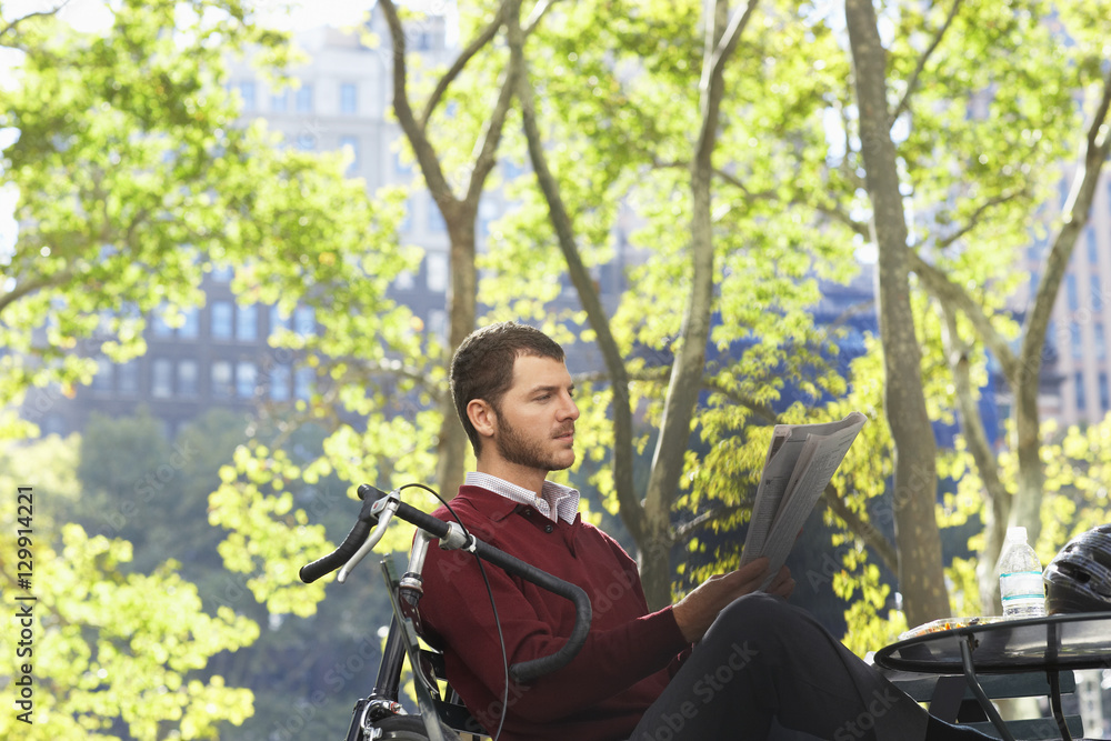 Young businessman reading newspaper in park Young businessman reading newspaper in park