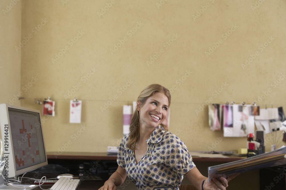 Smiling young woman handing off documents in office Smiling young woman handing off documents in office