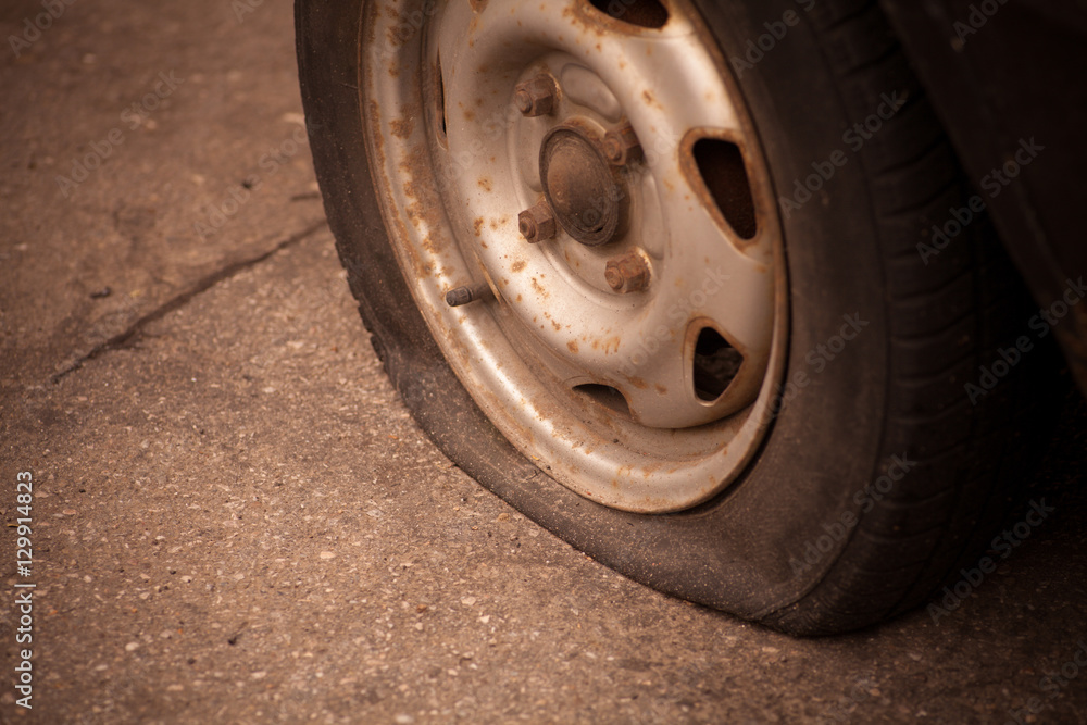 Close up shot of a car with a flat tire.