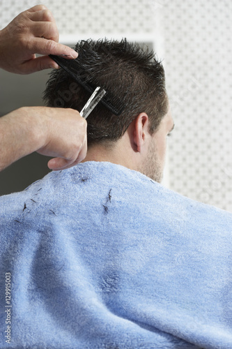 Closeup of hairdresser cutting man's hair in barber shop