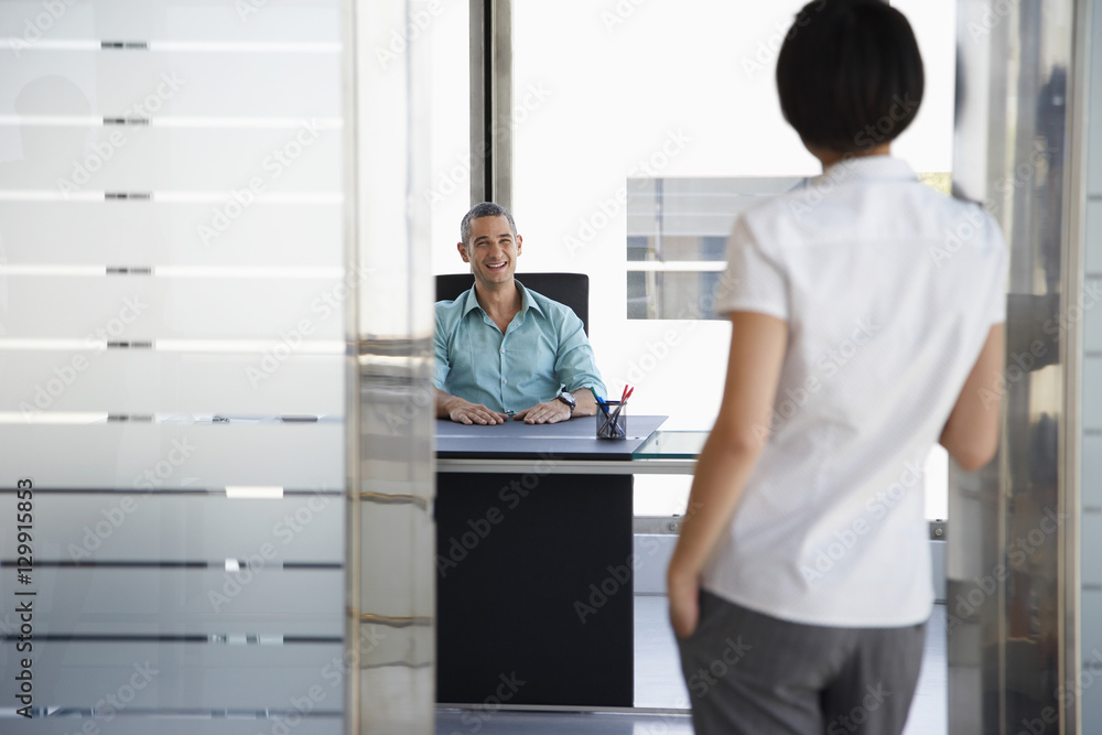 Fototapeta premium Smiling young man talking to woman standing in doorway at his office