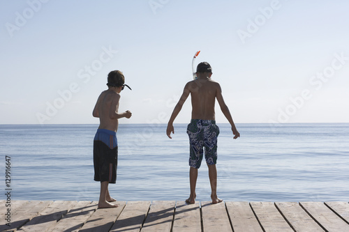 Rear view of two boys with snorkeling masks on jetty