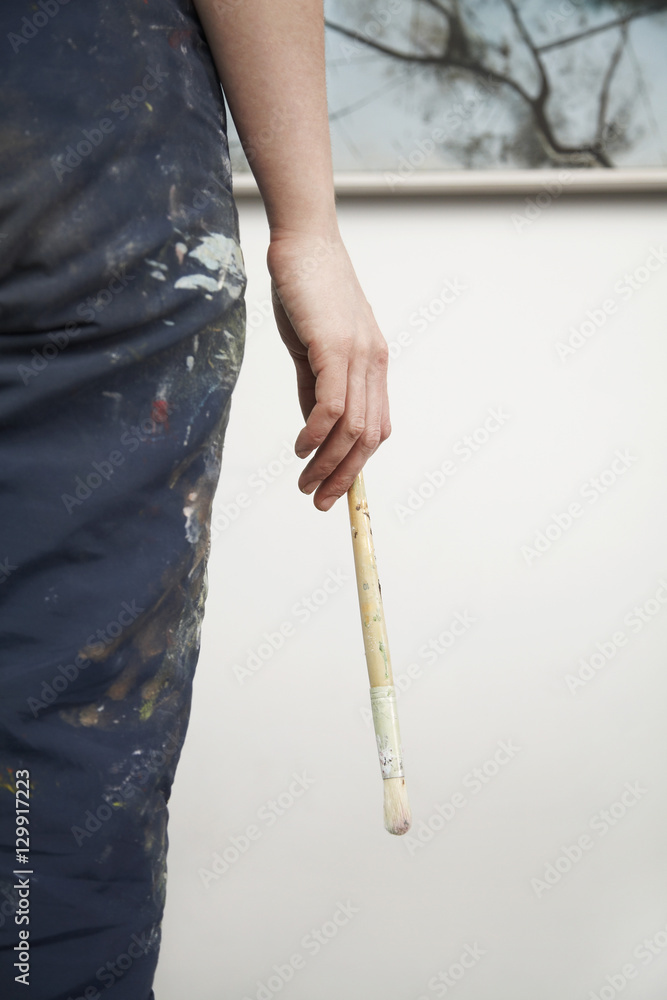 Midsection of female artist holding paintbrush