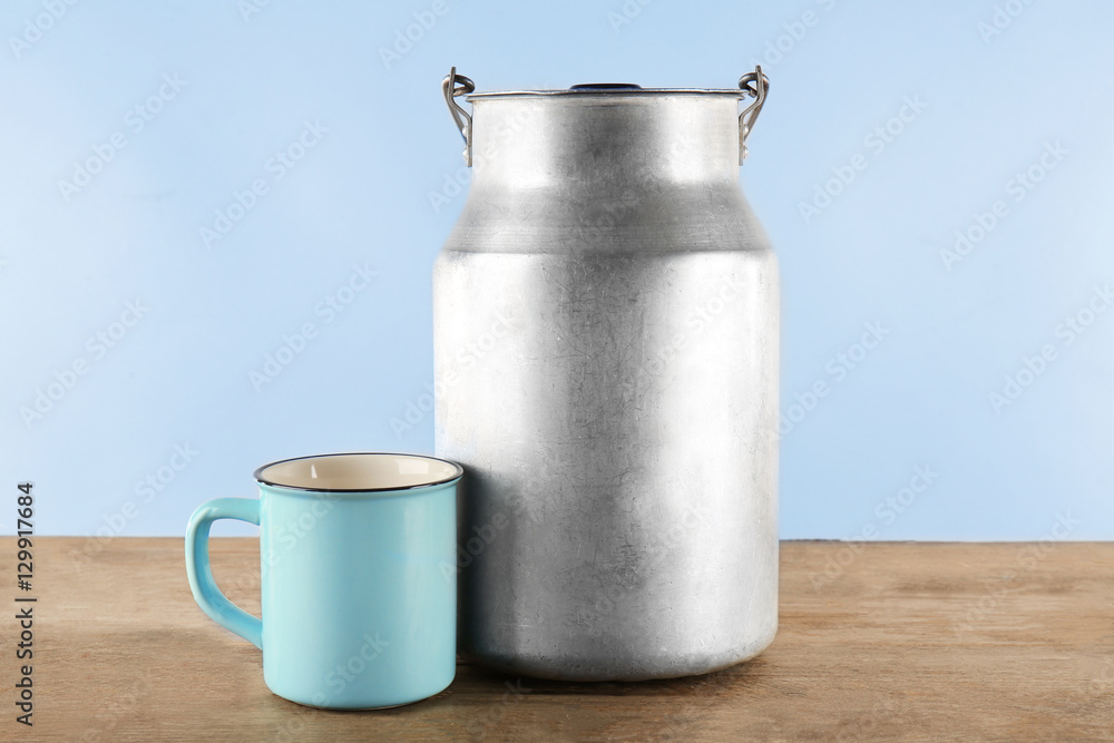 Aluminium milk can with cup on wooden table Aluminium milk can with cup on wooden table