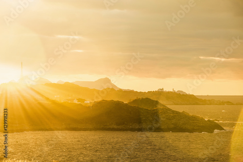 Mountains, ocean. Rocky island in the ocean. Sunset, sunlight, sun rays. © scharfsinn86