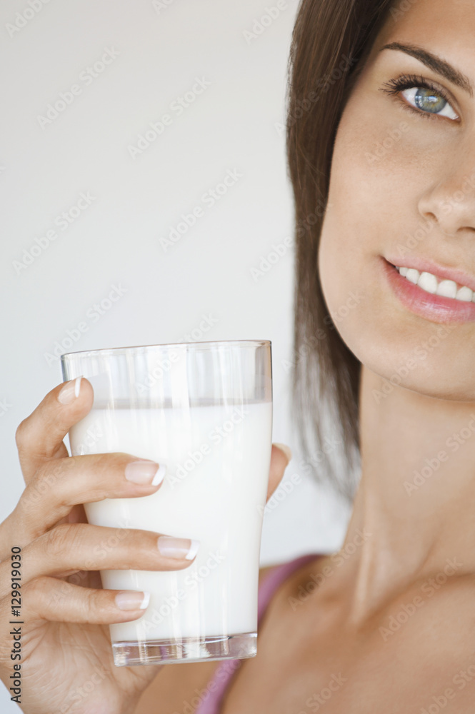Closeup portrait of a cropped young woman holding glass of milk Closeup portrait of a cropped young woman holding glass of milk