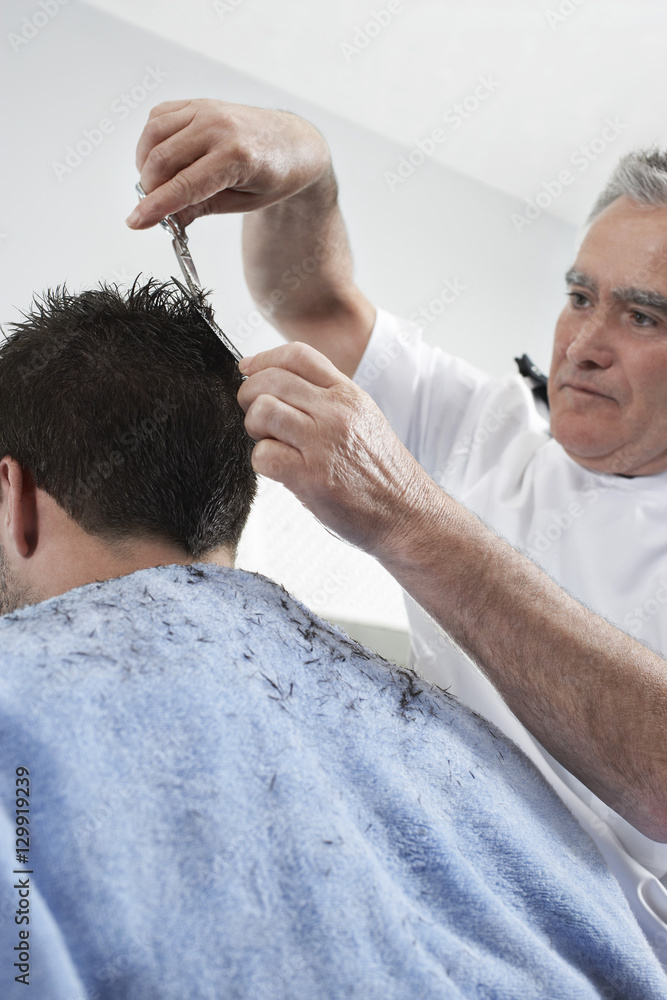 Senior hairdresser cutting man's hair in barber shop Senior hairdresser cutting man's hair in barber shop