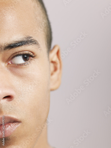 Closeup of young African American man looking sideways on colored background