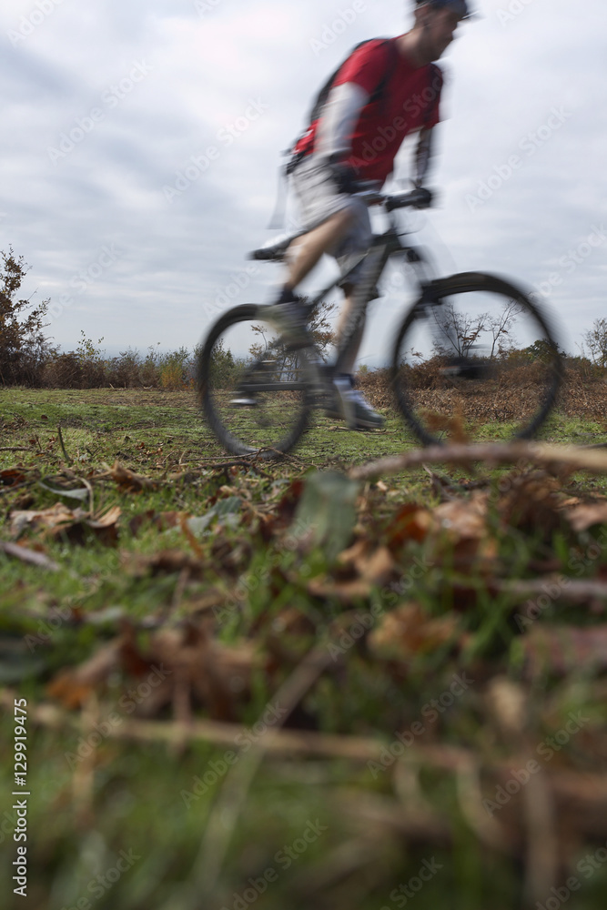 Fototapeta premium Blurred motion of man riding mountain bike on countryside