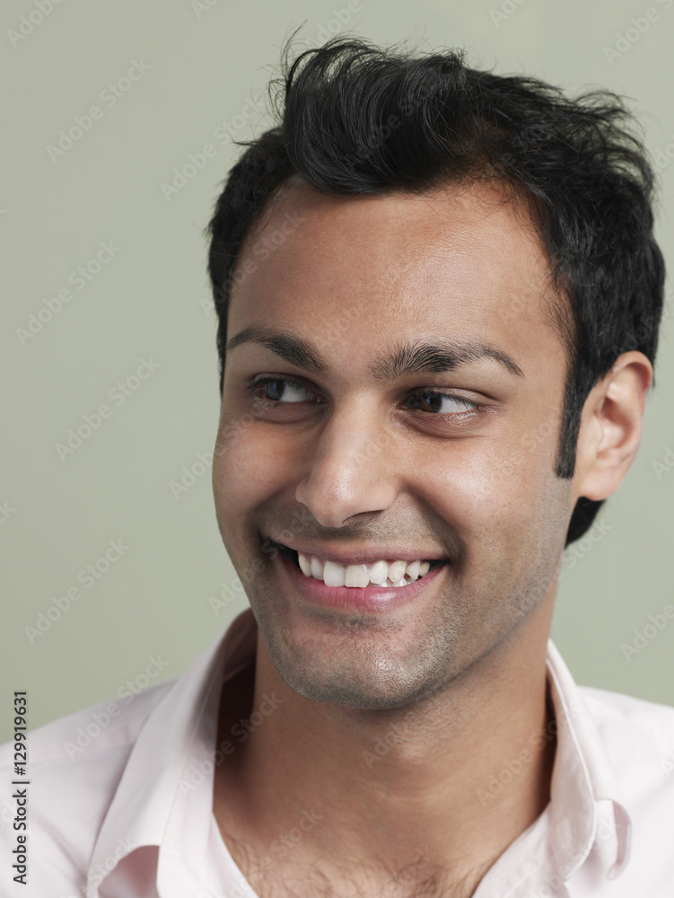 Obraz premium Closeup of young Asian man looking away and smiling on colored background