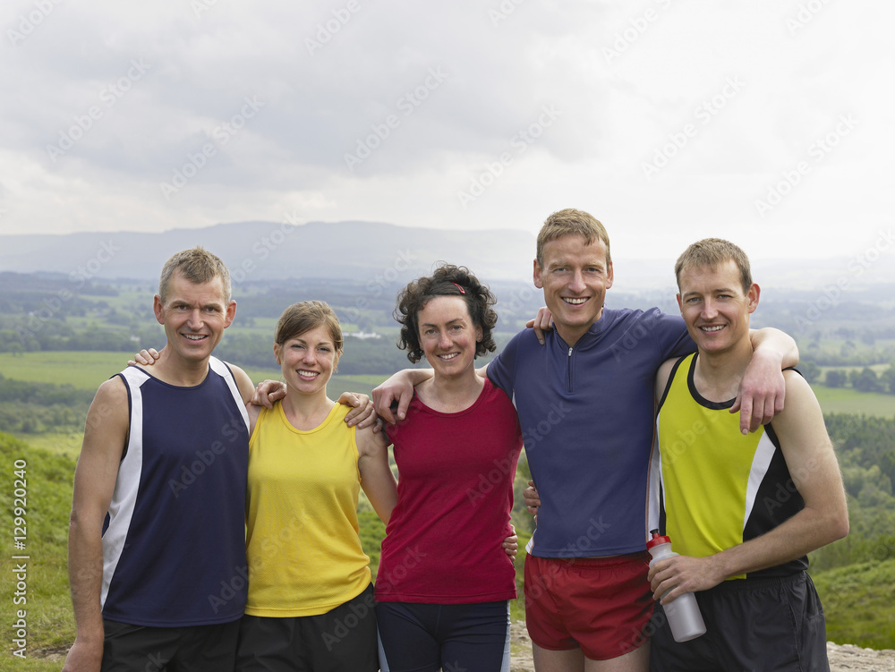 Group portrait of smiling hikers with arms around on country landscape Group portrait of smiling hikers with arms around on country landscape